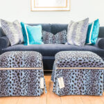 gray and blue leopard print stools in front of a dusty blue velvet couch with more leopard print and blue pillows