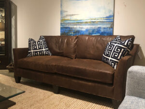 Brown leather Stanford couch with black and white patterned pillows