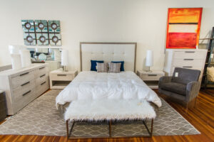 low bench with a shaggy white top in front of a bed with a square headboard