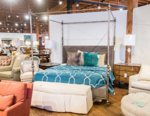 upholstered white bench in front of a canopy bed with a teal bedspread