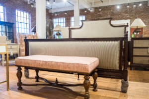 dark brown wood bench with a peach colored cushion in front of a traditional bed frame