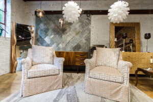 two cream armchairs with geometric patterns placed on a rug in front of a dresser