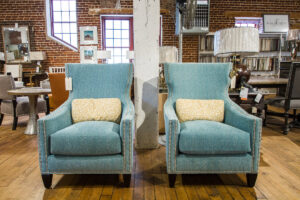 two blue armchairs sitting side by side, each with a light yellow pillow, sitting on hardwood floors