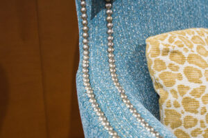 up close image of the arm of a blue chair with silver metal details