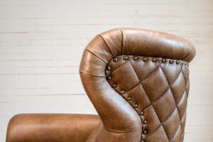 up close side profile of a brown leather chair with a quilted leather back
