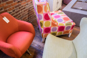 three chairs in green front furniture showroom. left chair is red, middle has a circular pattern, and right is taupe colored