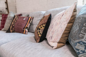 pink, bronze, red, orange, and black patterned pillows on a gray sofa